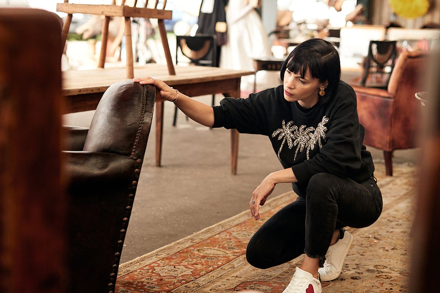 A woman is looking at the back of a brown leather chair.