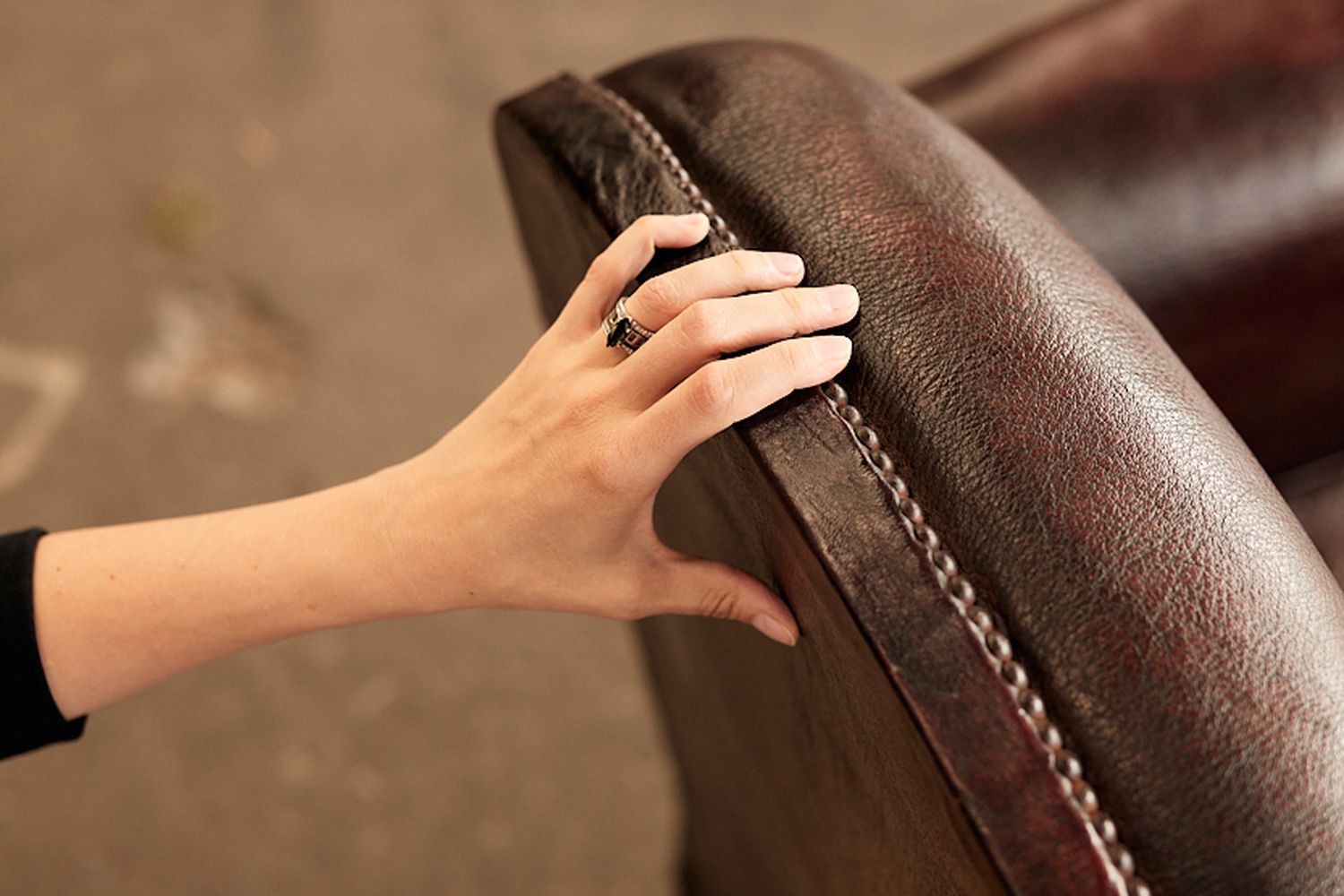 A hand on a brown leather chair.