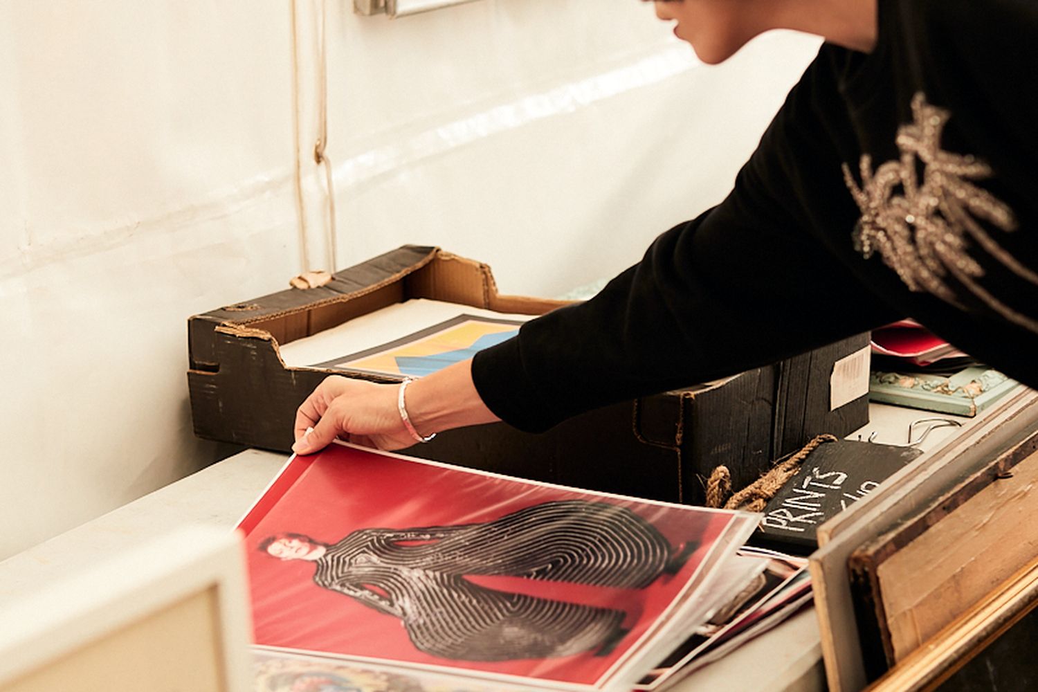 A woman is looking at a print of David Bowie with a red background.