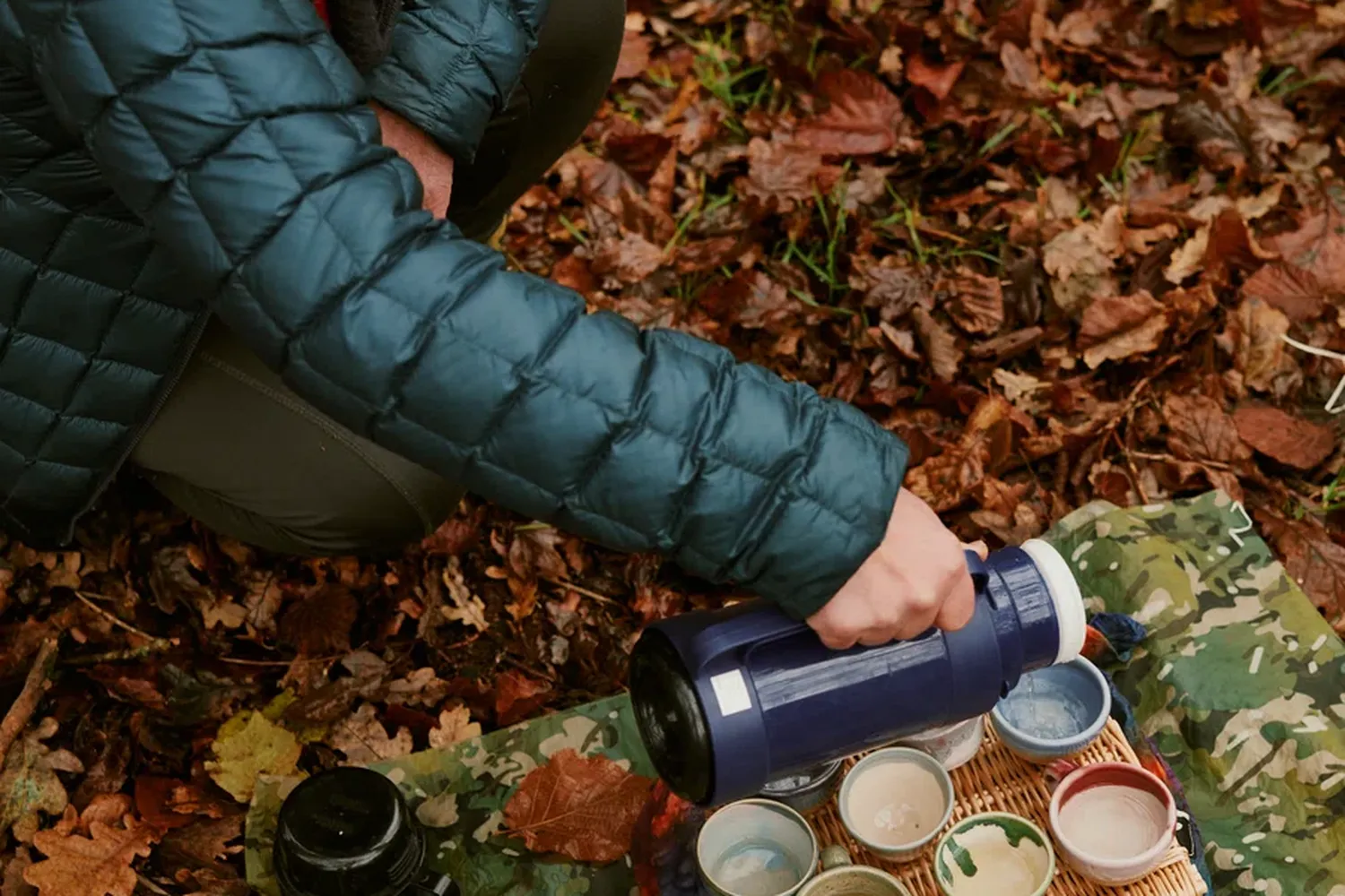 Camping in the woods, enjoying a cup of tea with a blue kettle. [G]