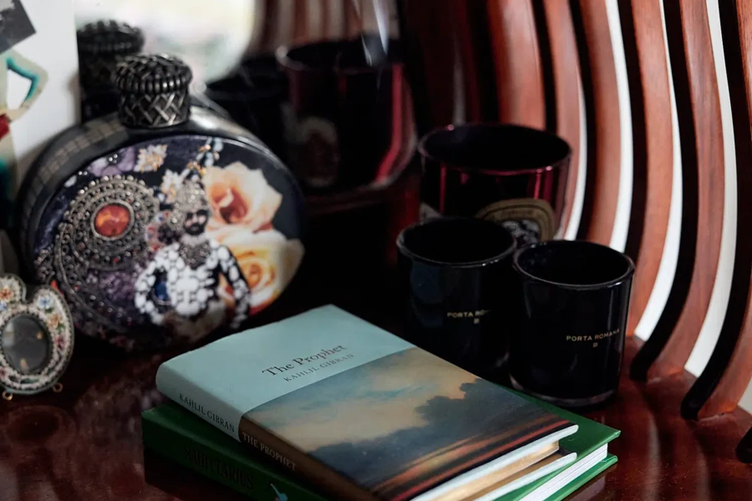 A book titled "Wol-Lindaboronkay" is placed on a green bookcase. There are three black cups on the table, and a black and white clock is also present. [G]