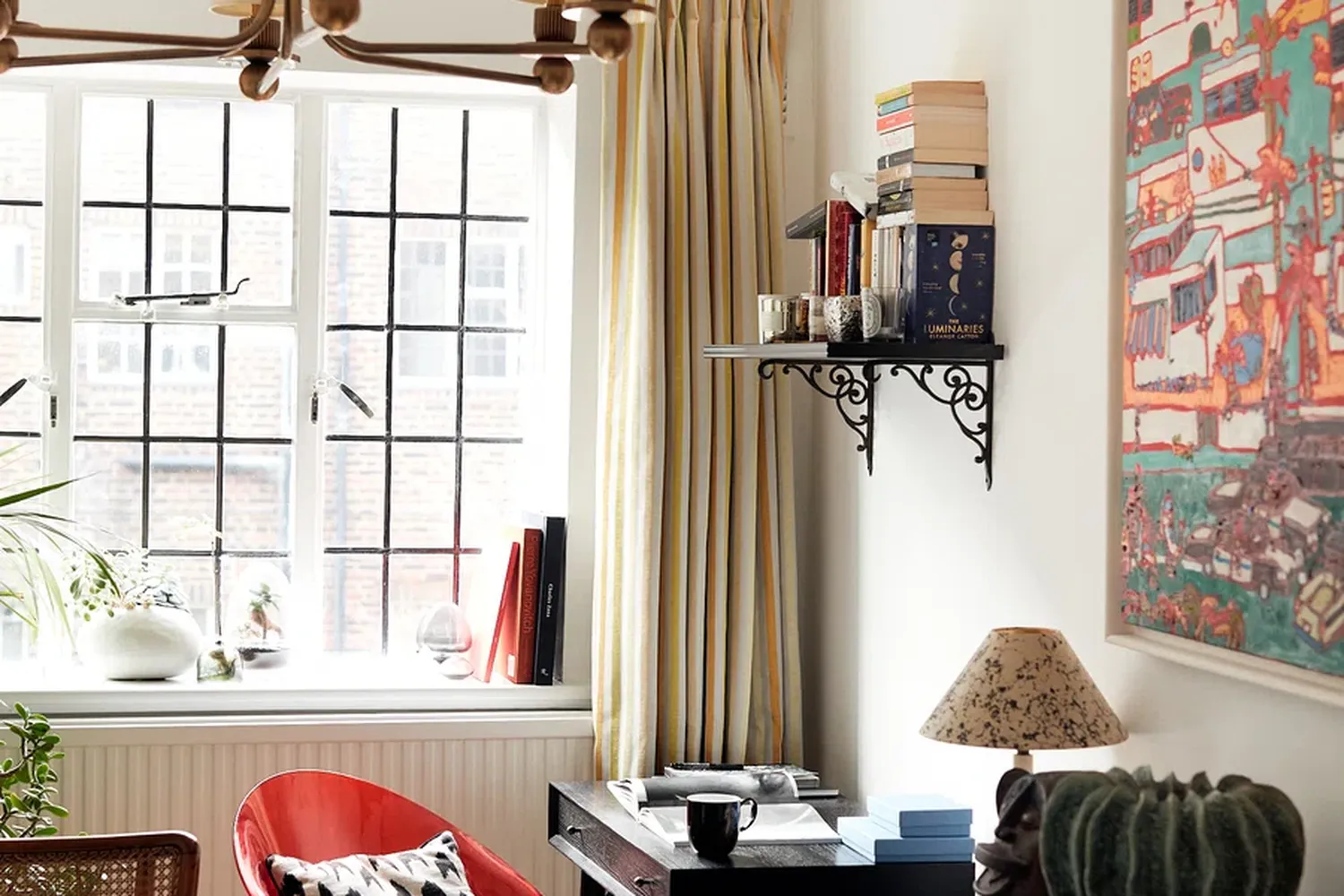 A room with a window, a lamp, a chair, a bookshelf, a plant, and a lampshade. [G]