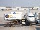 A plane at the gate with two LSG catering trucks parked next to it