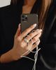 Person in black holds a smartphone with tangled white earphones, showcasing freshly manicured nails.