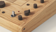Close-up of a wooden electronic device with dark knobs, a metallic switch, and a small red indicator on a light surface.
