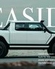 A white pickup truck is parked by the seaside, with text highlighting its sustainable power and coastal performance.