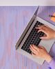 A close-up of a person typing on a laptop, framed in a blue graphic