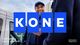 The KONE logo in front of a smiling man