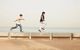 Two kids running alongside a path with the sea behind them