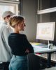 Two people standing in front of a computer monitor