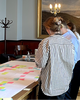 Two person at a table looking down at a poster with post-its on it