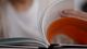 Close-up of an open book being held, with pages flipping. One page has a bright orange background contrasting with the white text.