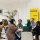 People sitting around two circular tables at a workshop, with a Vueling sign in the background