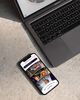 A phone on a table next to a laptop, scrolling through an interactive wheel with images