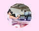 An image of a woman in an office using a VR headset and holding her hand up towards a laptop. The image is placed inside a light pink circular cut out shape.