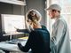 Two people in an office pointing at a screen