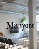 A bright, industrial office space with the decal 'Manyone' on a glass door