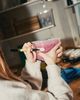Person labeling a container of pink liquid in a dimly lit kitchen, surrounded by various objects.