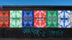 Series of colorful posters on a wall advertising the Heartland event from June 18-20, 2026, with graffiti below.