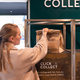 A person picking up a paper bag from a bakery. There is a sign that reads "click and collect" on a green background.