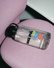 A water bottle on a pink chair with the text 'RIG PÅ' and three colorful shapes with the text 'pauser,' 'glæde,' and 'erfaring'