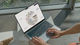 A close up of a person's hands on a laptop, open to a compass with the TrygFonden logo in the center