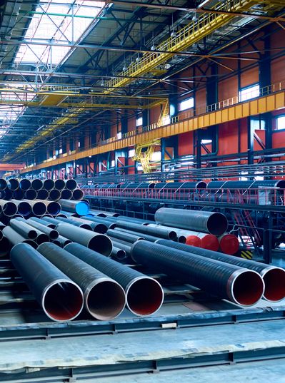 Interior of a large industrial warehouse with stacks of metal pipes