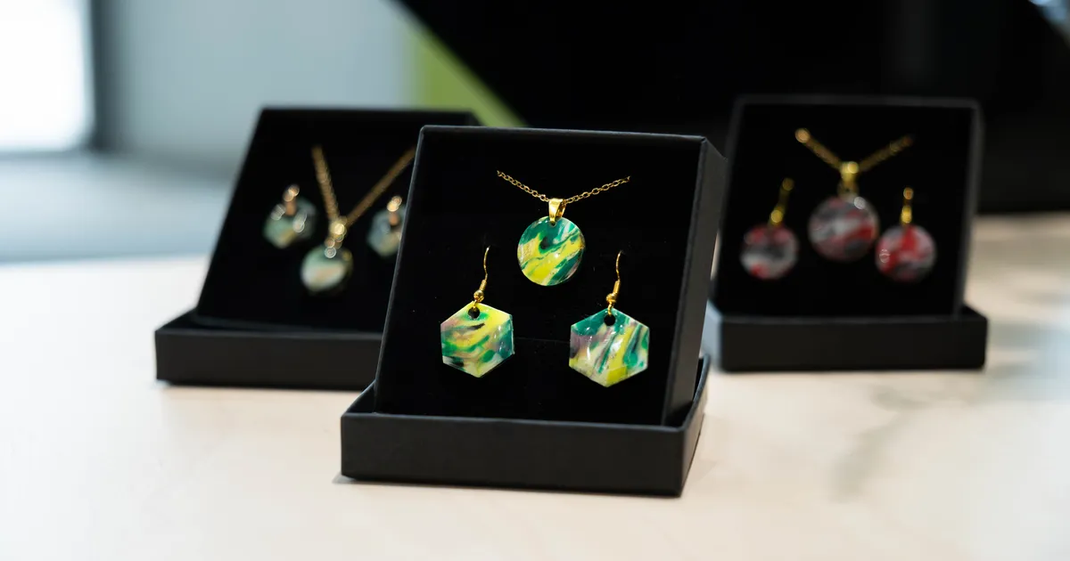 Produktfoto zeigt Schmuckschatullen mit je zwei Ohrhängern und einem Anhänger aus gepressten, bunten Kunststoffresten