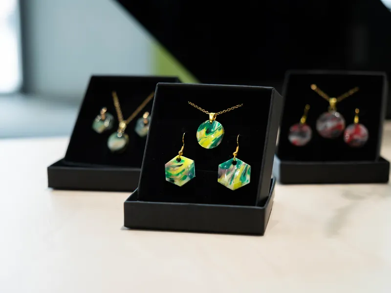 Produktfoto zeigt Schmuckschatullen mit je zwei Ohrhängern und einem Anhänger aus gepressten, bunten Kunststoffresten