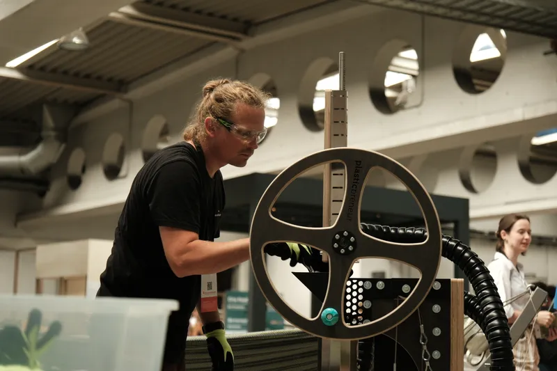 Mann mit Sicherheitsbrille bedient einen Plastikshredder mit Handkurbel