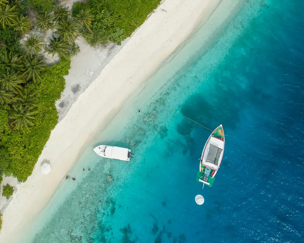 A top down image of two boats close to the Caribbean shore