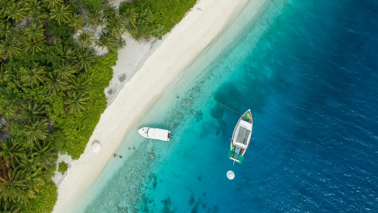 A top down image of two boats close to the Caribbean shore