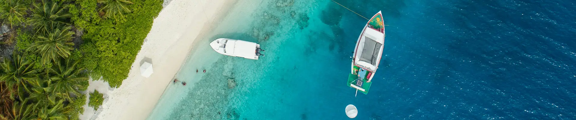 A top down image of two boats close to the Caribbean shore