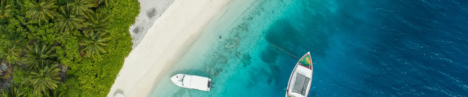 A top down image of two boats close to the Caribbean shore