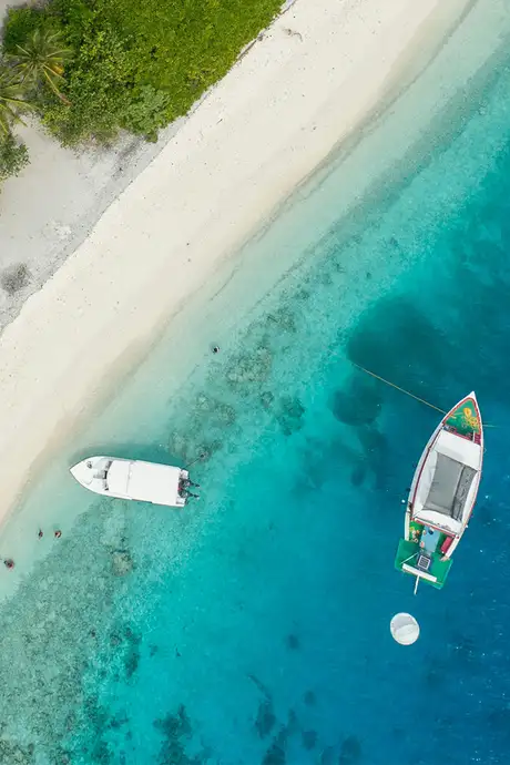 A top down image of two boats close to the Caribbean shore
