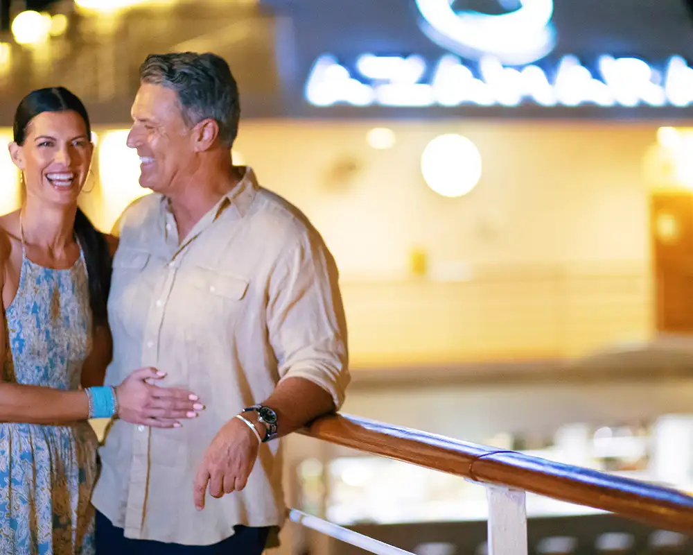 A couple leaning on a railing on a Azamara ship