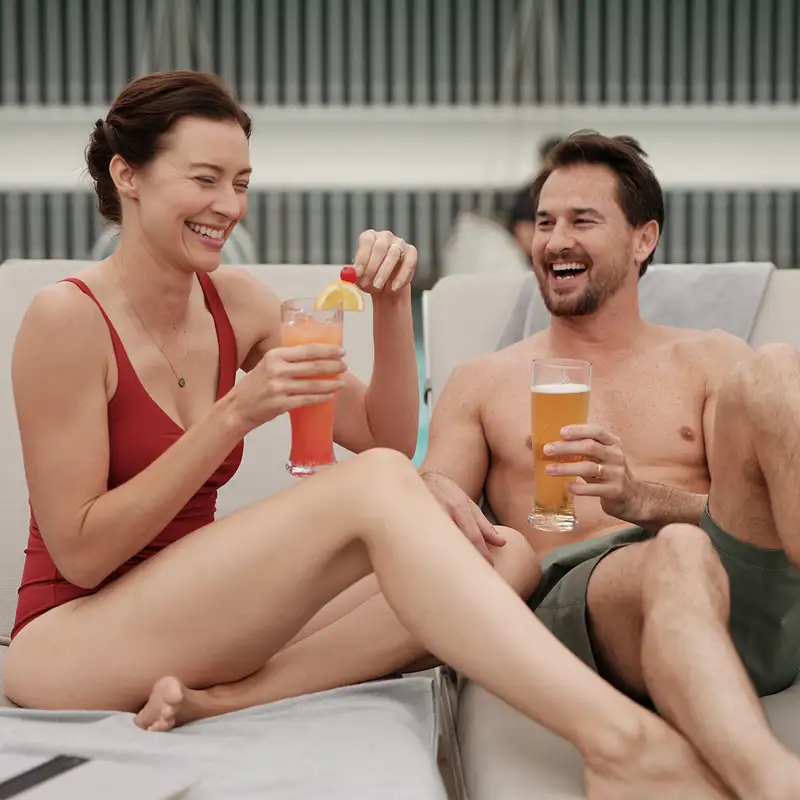A couple enjoying drinks by a pool on a Celebrity Ship