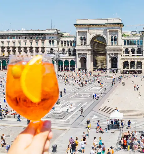 Someone holding a drink and overlooking a courtyard of people