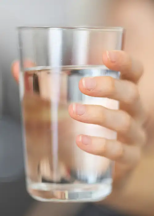A person holding a glass of water towards the camera