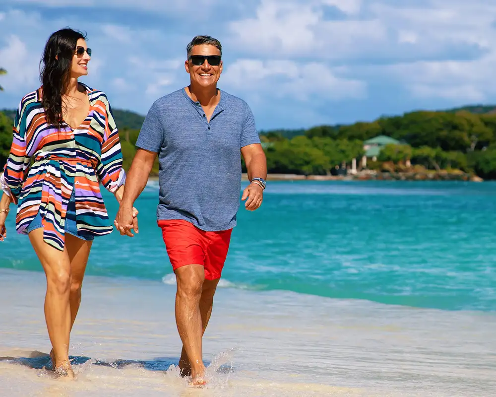 A couple walking down the shore of a beach on an Azamara holiday