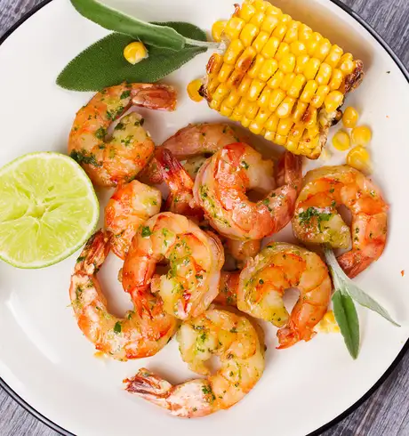 A serving of prawns with a lime slice and a corn on the cob