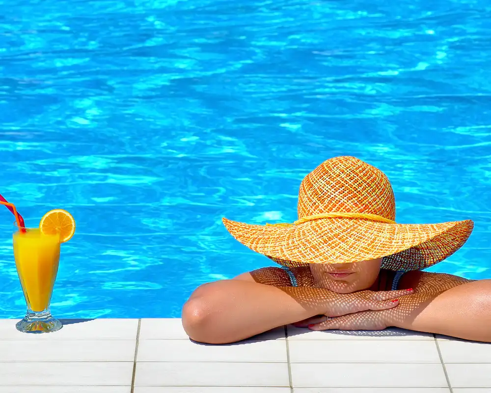 A woman relaxing in a pool with an orange drink