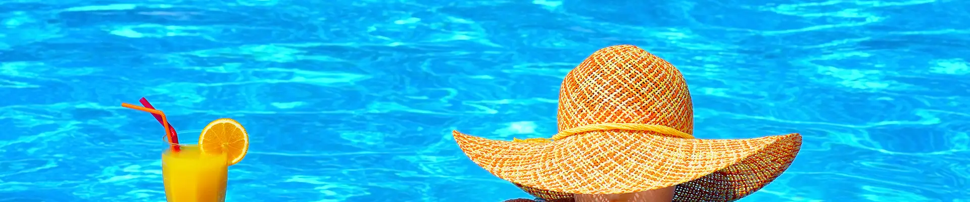 A woman relaxing in a pool with an orange drink