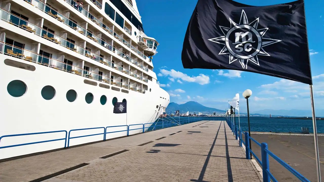 An MSC Cruise ship docked with an MSC logo on a flag at the port