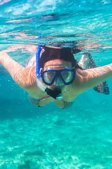 A woman snorkeling through crystal clear water