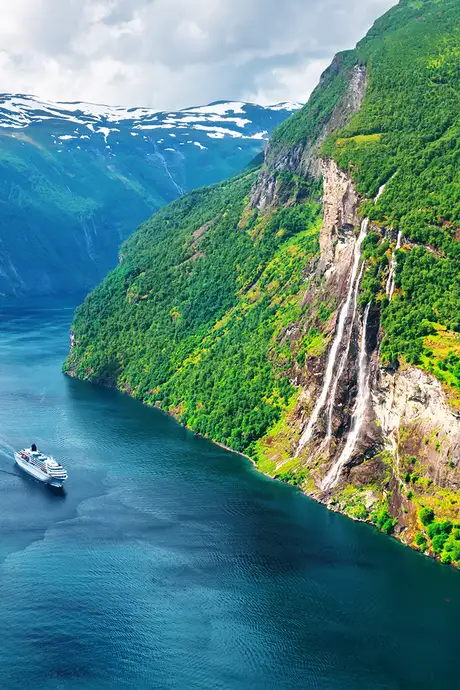 An image of a cruise ship sailing through a fjord