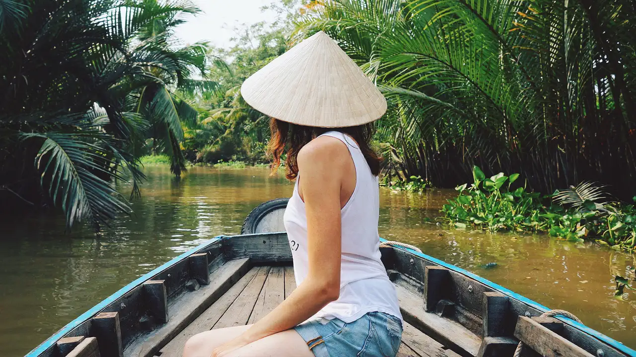 A woman in a boat riding down the Mekong Delta River