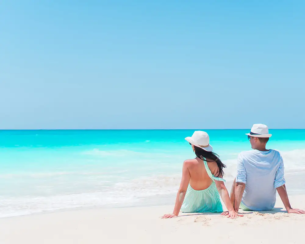 A couple sitting by the shore, relaxing on a Caribbean beach