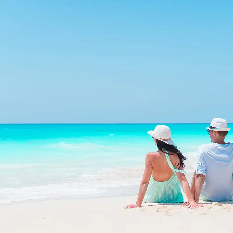 A couple sitting by the shore, relaxing on a Caribbean beach