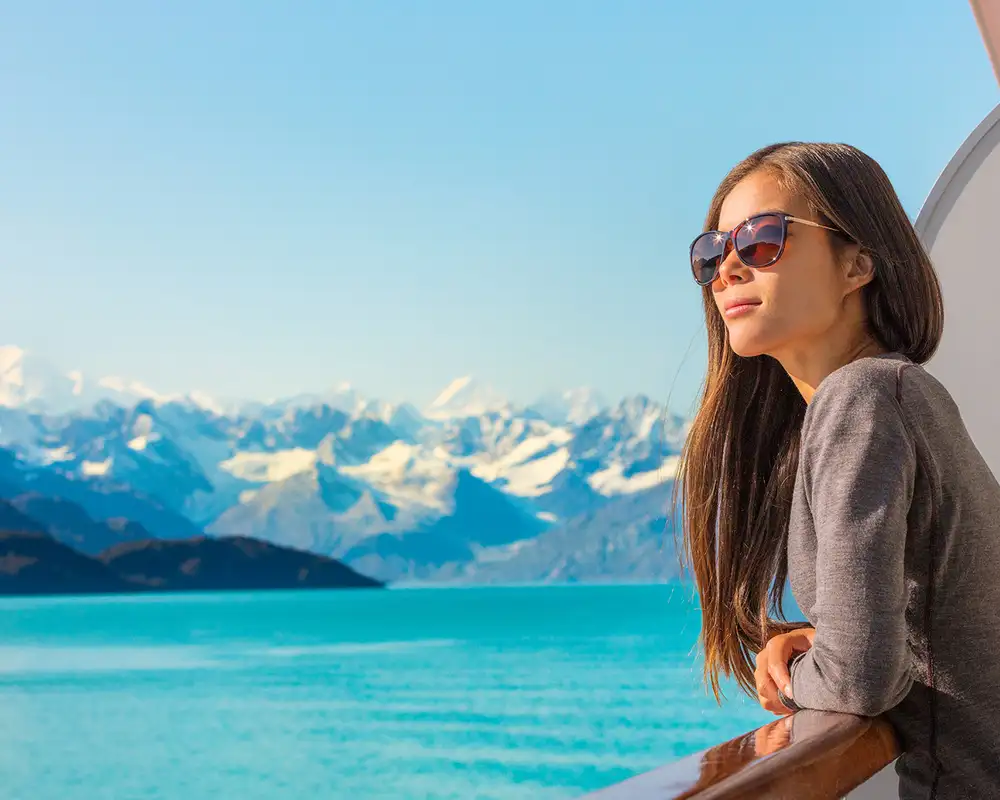 A Woman looking out over the balcony of a cruise ship at Alaska